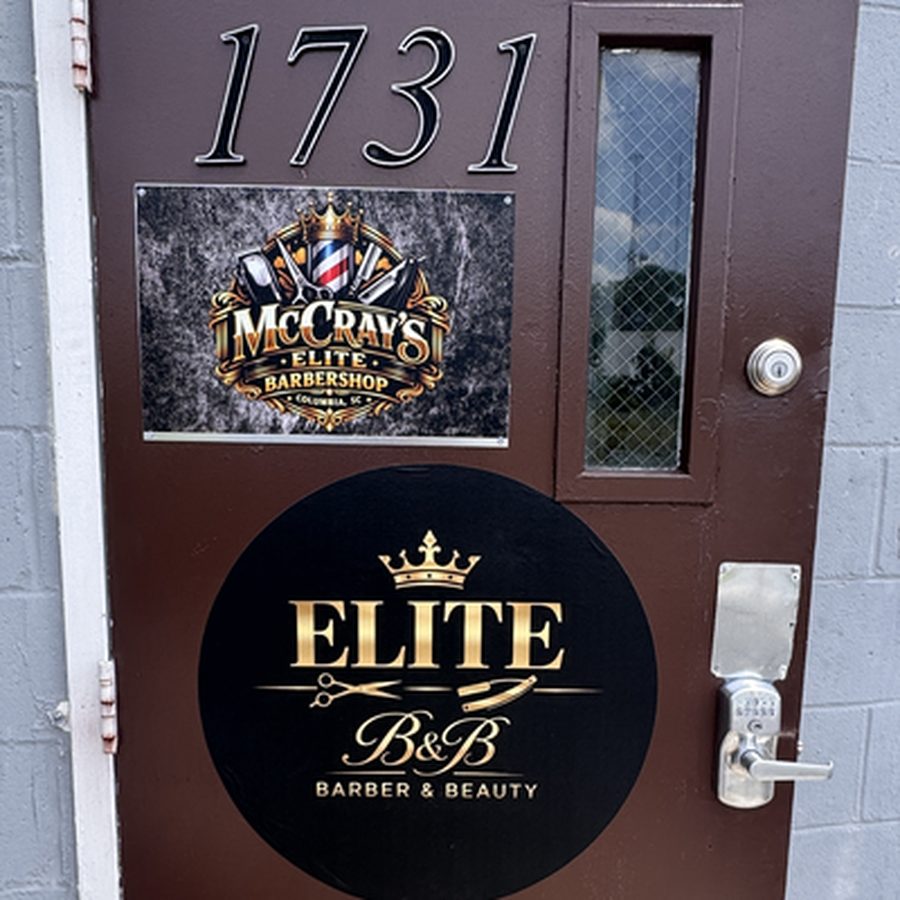 The barber door at 1731 Risley Rd, carrying the McCray's Elite Barbershop plaque and the Elite Barber and Beauty crown medallion