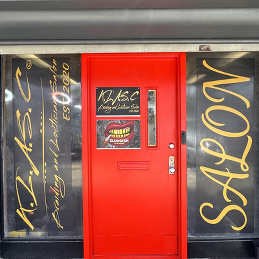 The red KLASC Braiding and Loctician Salon door at 1731 Risley Rd, between the two painted salon windows